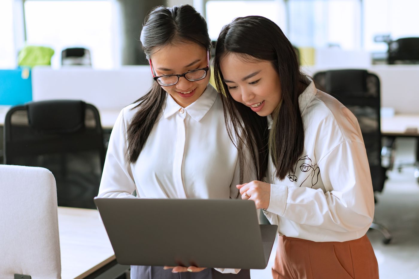 Colleagues discussing a laptop with natural smiles